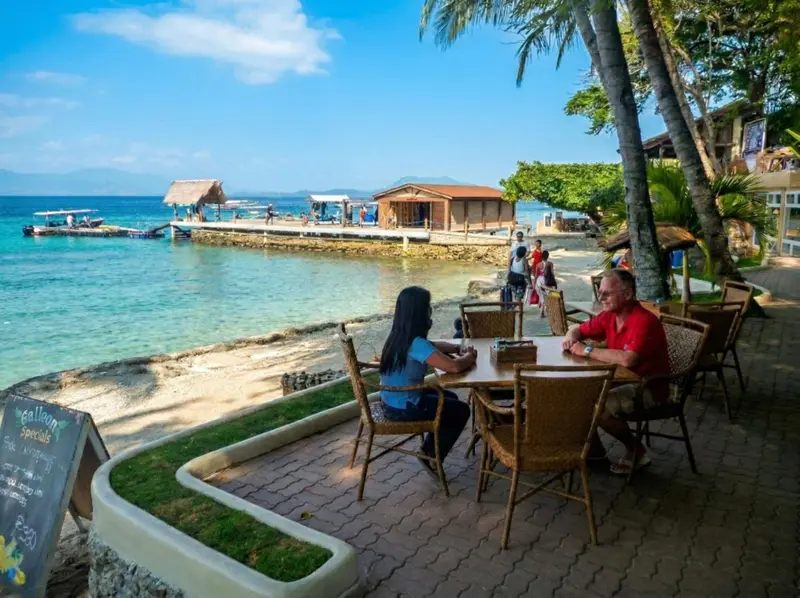 Deux personnes sont assises à une table sur une terrasse en bord de mer.