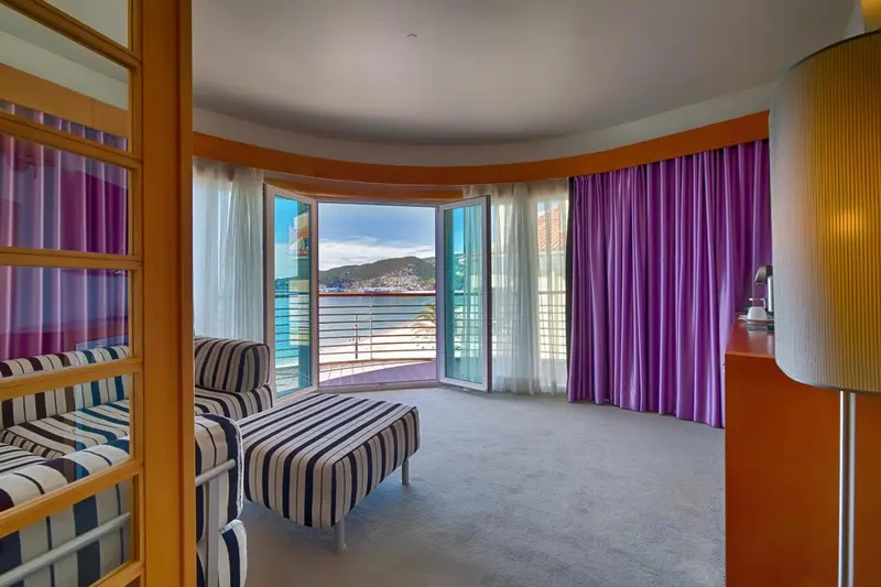 Une chambre lumineuse avec un coin salon et une vue sur la mer.