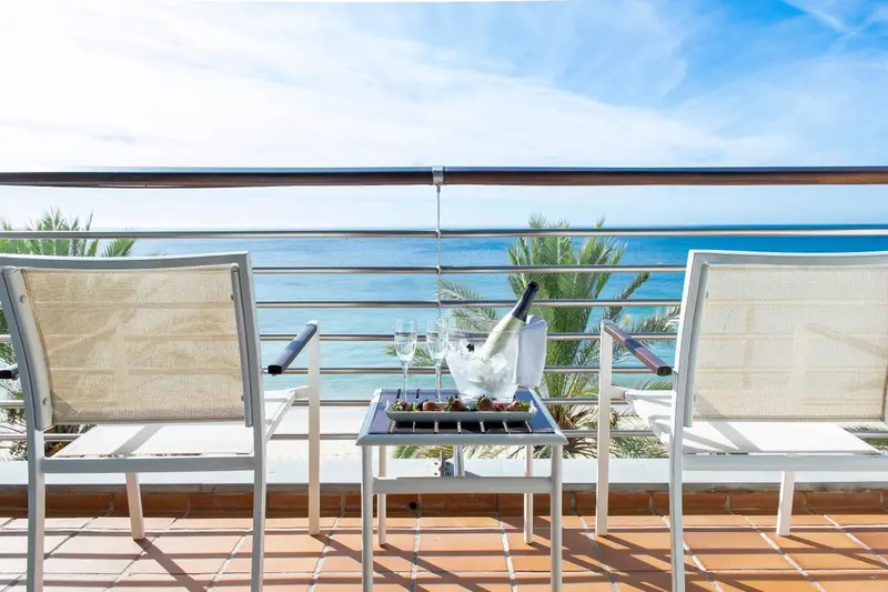 Deux fauteuils de terrasse offrent une vue dégagée sur la mer et le ciel bleu.