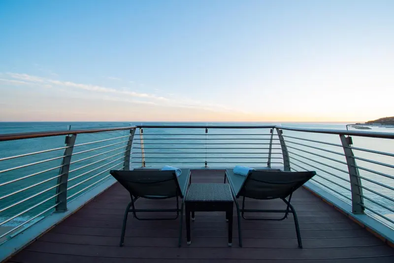 Terrasse avec mobilier d'extérieur donnant sur la mer au coucher du soleil.