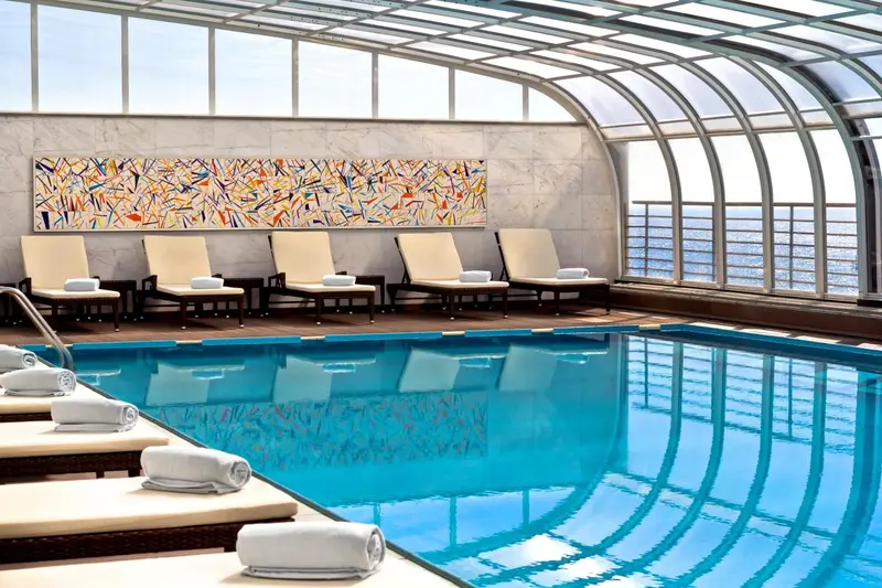 Une piscine intérieure lumineuse avec des transats et un tableau abstrait.