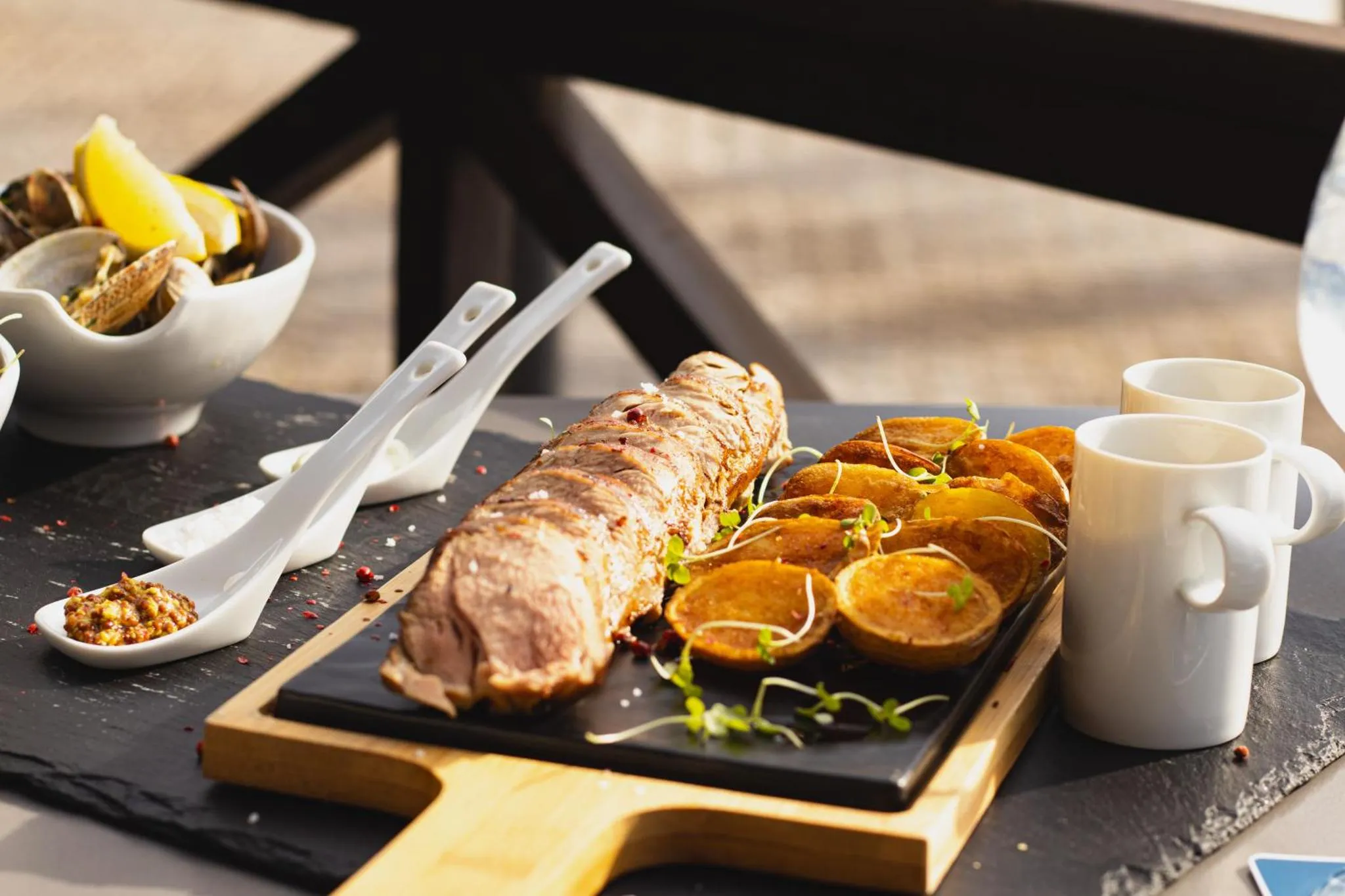 Un plat de poisson grillé est servi avec des accompagnements sur une ardoise.
