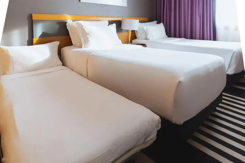 Deux lits jumeaux avec une literie blanche dans une chambre d'hôtel.