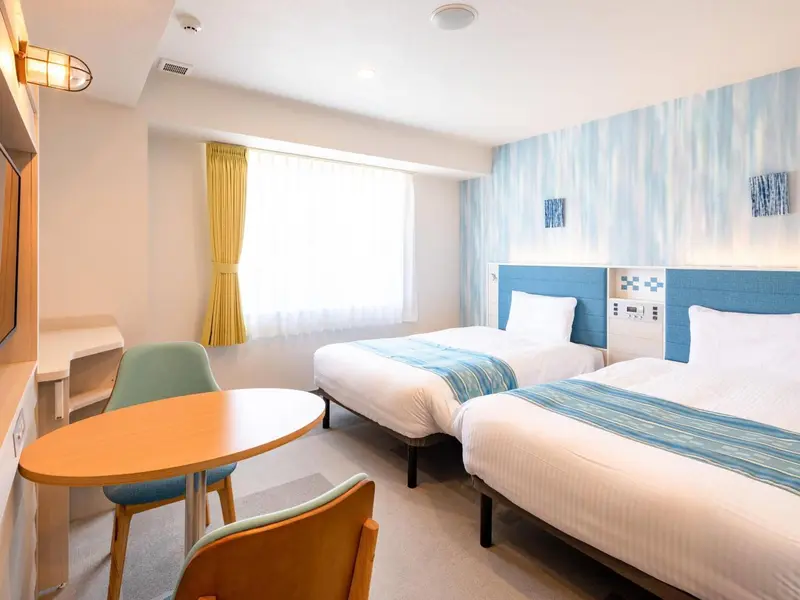 Une chambre lumineuse avec deux lits simples et un coin repas.