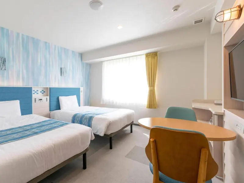 Une chambre lumineuse avec deux lits et un coin repas.