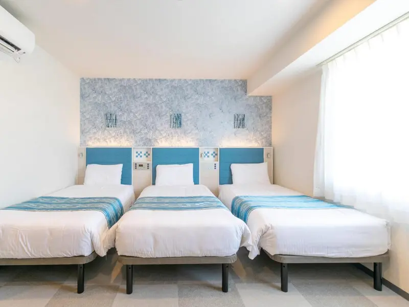 Une chambre avec trois lits simples et une décoration murale bleue.