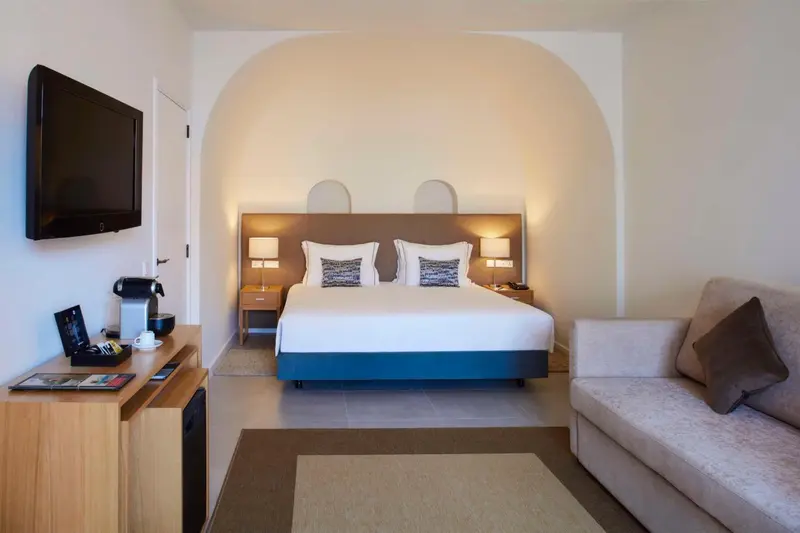 Une chambre lumineuse avec un grand lit et un coin salon.