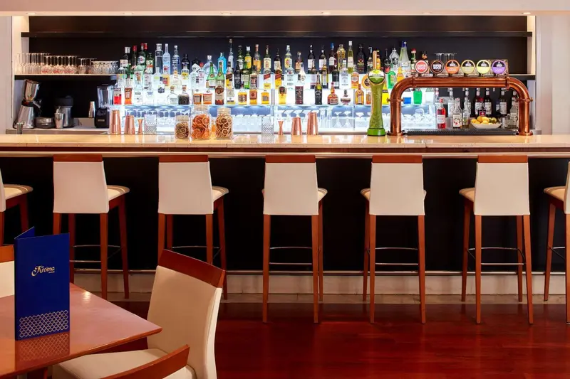 Un comptoir de bar moderne avec des tabourets et une large sélection de bouteilles.