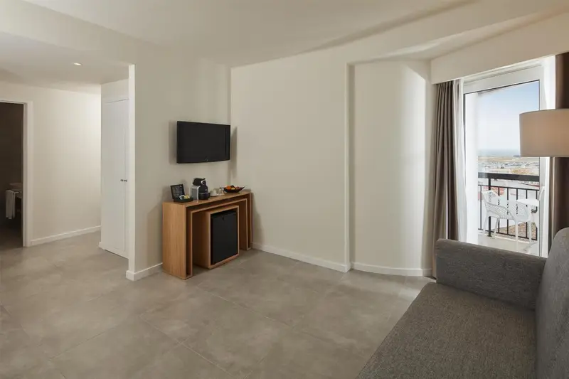 Une pièce lumineuse avec un canapé, une télévision et un balcon.