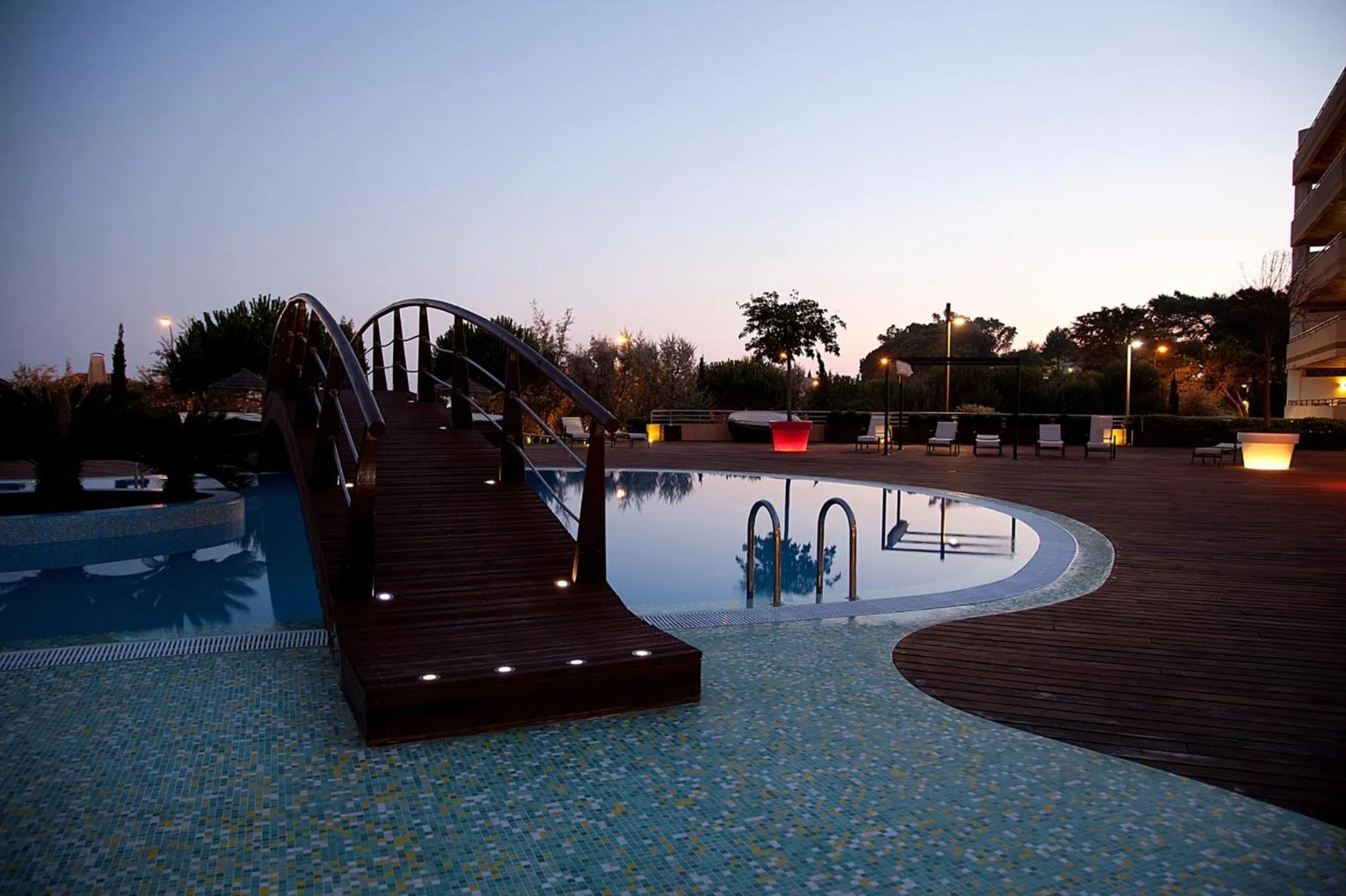 Une piscine rectangulaire avec un ponton en bois et des transats.