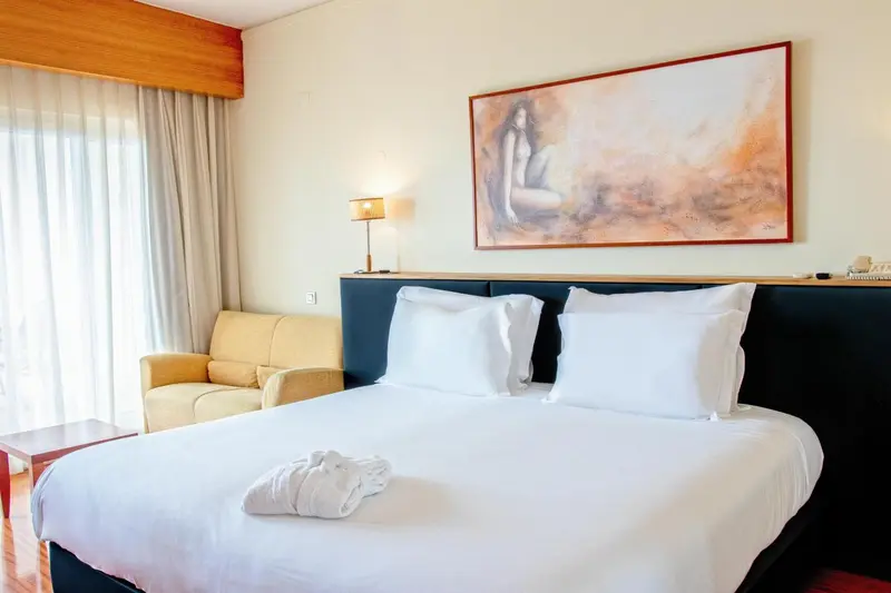 Une chambre lumineuse avec un grand lit et un fauteuil.