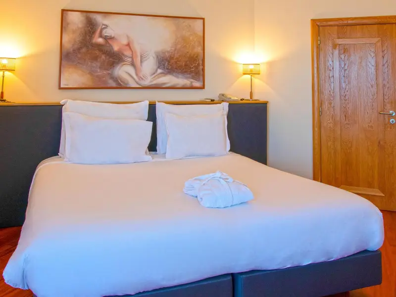 Une chambre avec un grand lit recouvert d'une courtepointe blanche et d'oreillers.