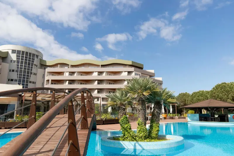 Bâtiment moderne avec des palmiers et une piscine au premier plan.