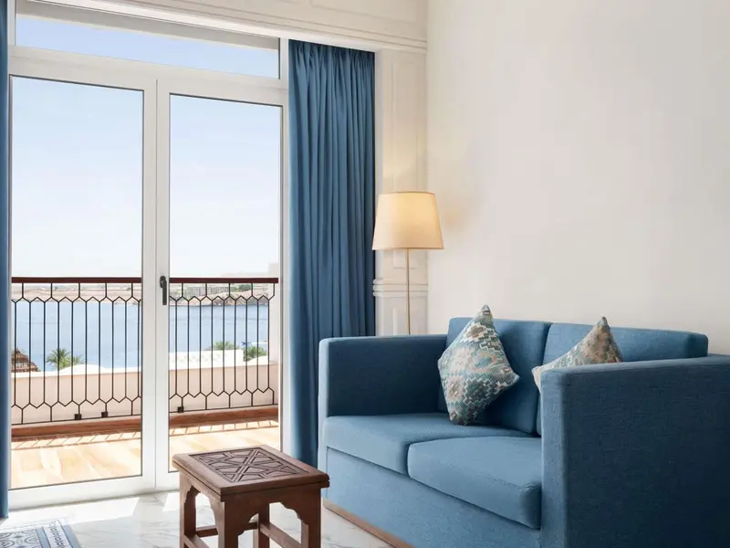 Une piece de sejour lumineuse avec un canape bleu et une vue sur la mer.