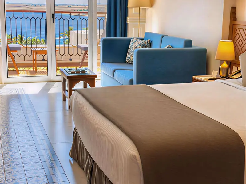 Une chambre lumineuse avec un canapé bleu et vue sur la mer.