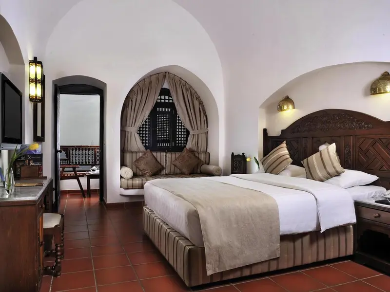 Une chambre à coucher lumineuse avec un grand lit et des arches décoratives.
