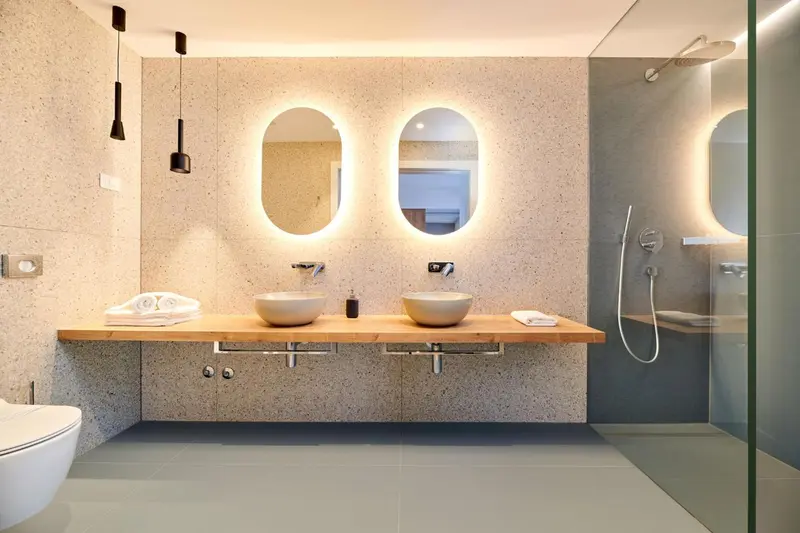 Une salle de bain moderne avec deux vasques et un grand miroir lumineux.