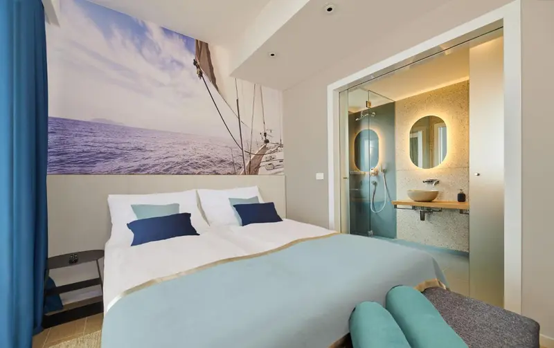 Une chambre lumineuse avec un grand lit et une salle de bain ouverte.