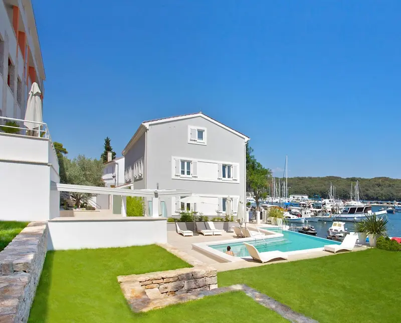Bâtiment blanc avec piscine et pelouse verdoyante en bord de mer.