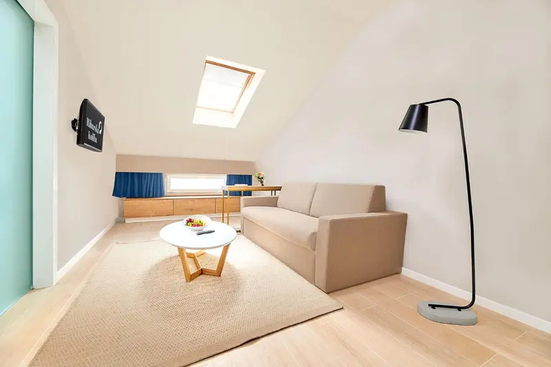 Une pièce lumineuse avec un canapé, une table basse et un téléviseur mural.