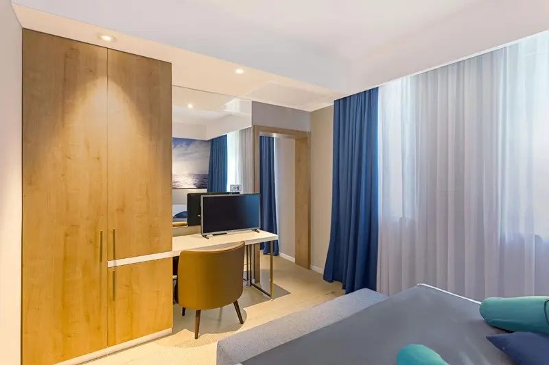 Une chambre lumineuse avec un bureau et un grand placard.