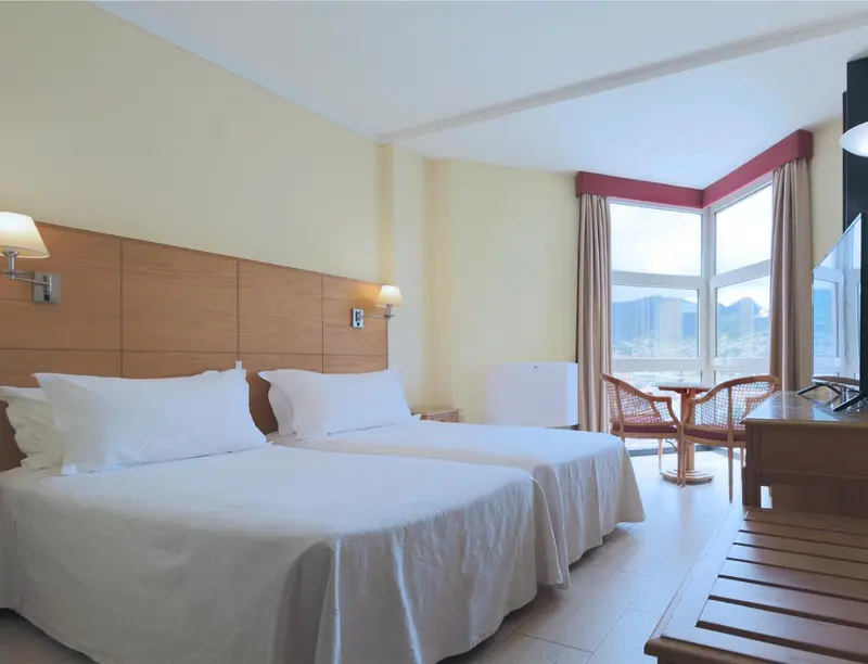 Une chambre lumineuse avec un grand lit et un coin salon près d'une fenêtre.