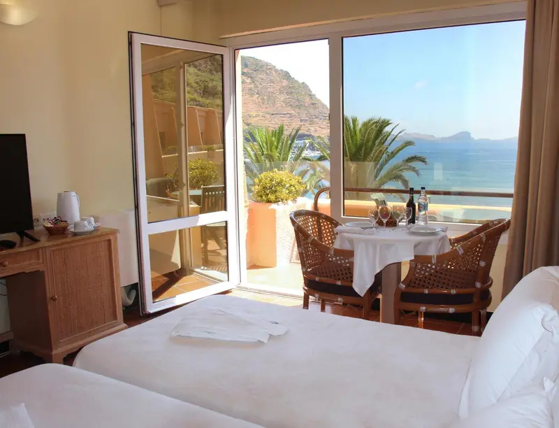 Une chambre lumineuse s'ouvre sur une terrasse avec vue sur la mer.
