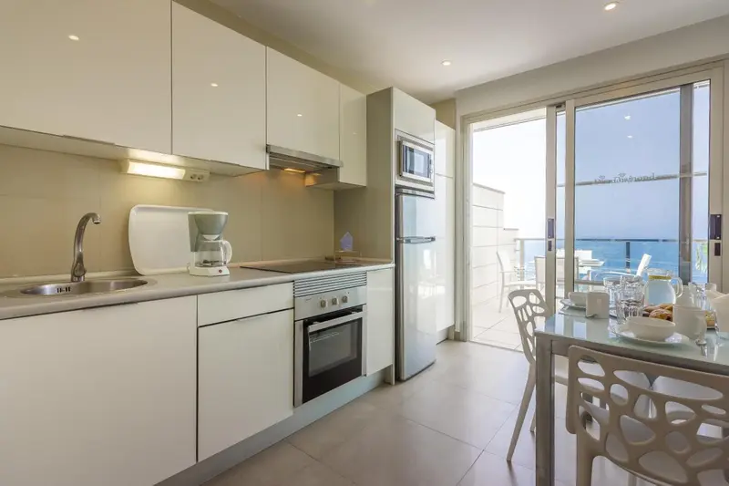 Une cuisine moderne s'ouvre sur une terrasse avec vue sur la mer.