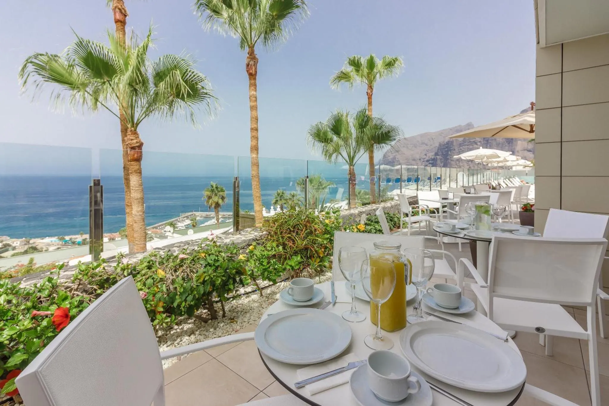 Une table est dressée pour le petit-déjeuner avec vue sur la mer et les montagnes.