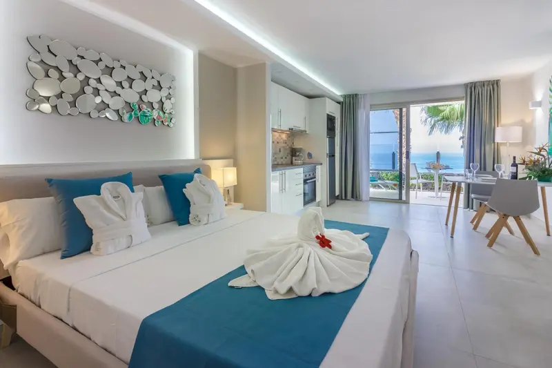 Chambre lumineuse avec lit décoré et vue sur la mer.