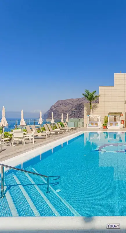 Terrasse avec piscine et chaises longues face à la mer.
