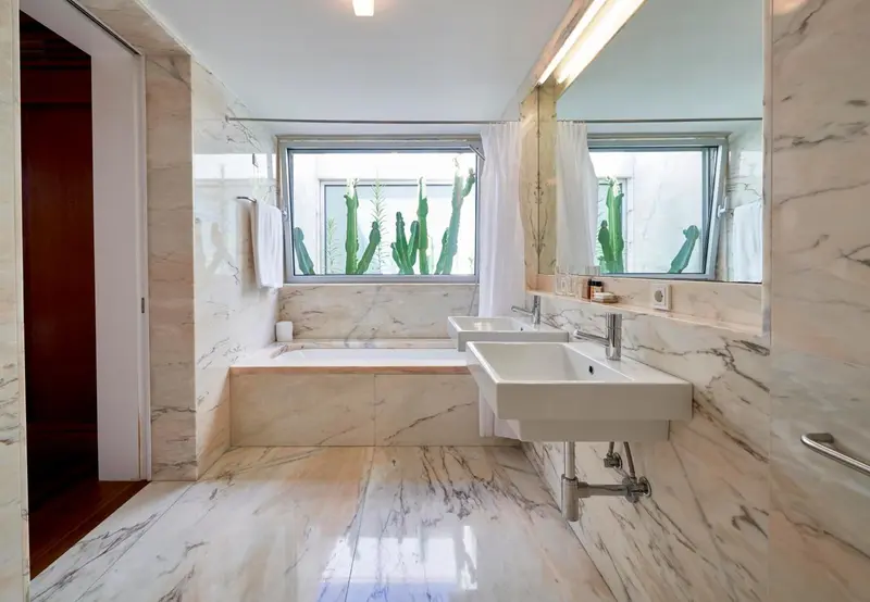 Une salle de bain lumineuse avec baignoire et deux vasques en marbre.
