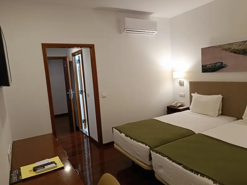 Une chambre lumineuse avec deux lits simples et une décoration sobre.
