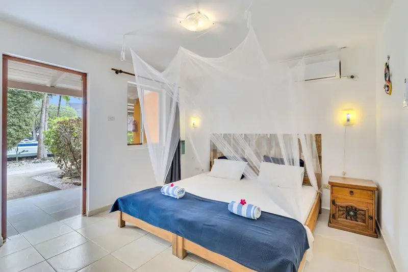 Une chambre lumineuse avec un lit à baldaquin et une vue sur la végétation.