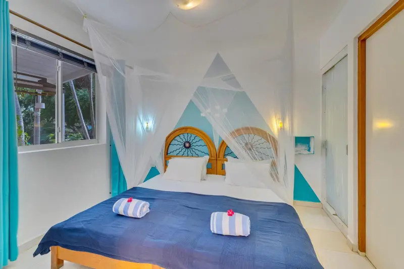 Une chambre lumineuse avec un lit à baldaquin et une décoration tropicale.