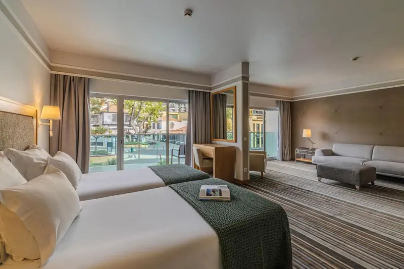 Chambre lumineuse avec un grand lit et un coin salon.