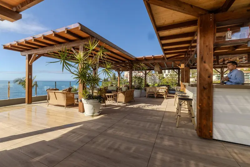Terrasse ombragée avec mobilier d'extérieur et comptoir de bar.
