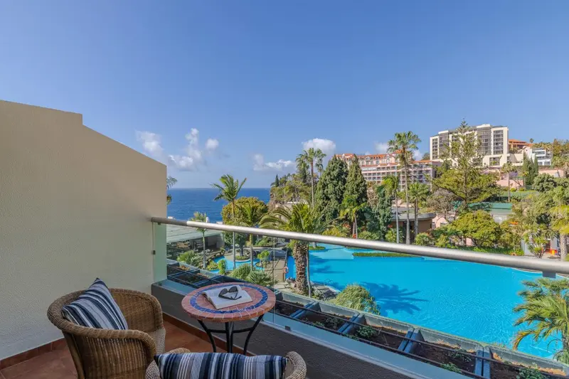 Une terrasse avec mobilier d'extérieur offre une vue sur la mer et une piscine.