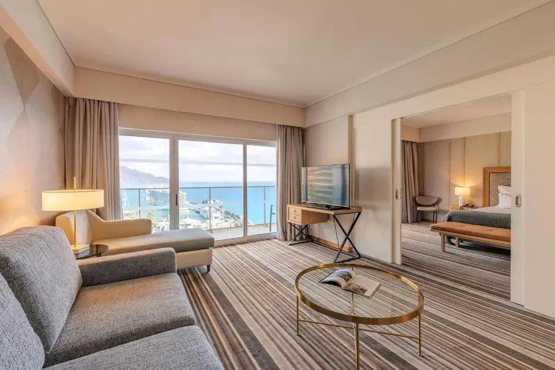 Espace de séjour lumineux avec canapé et vue sur la mer.