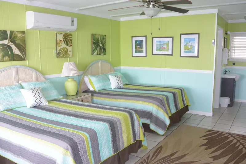 Une chambre lumineuse avec deux lits et une décoration tropicale.