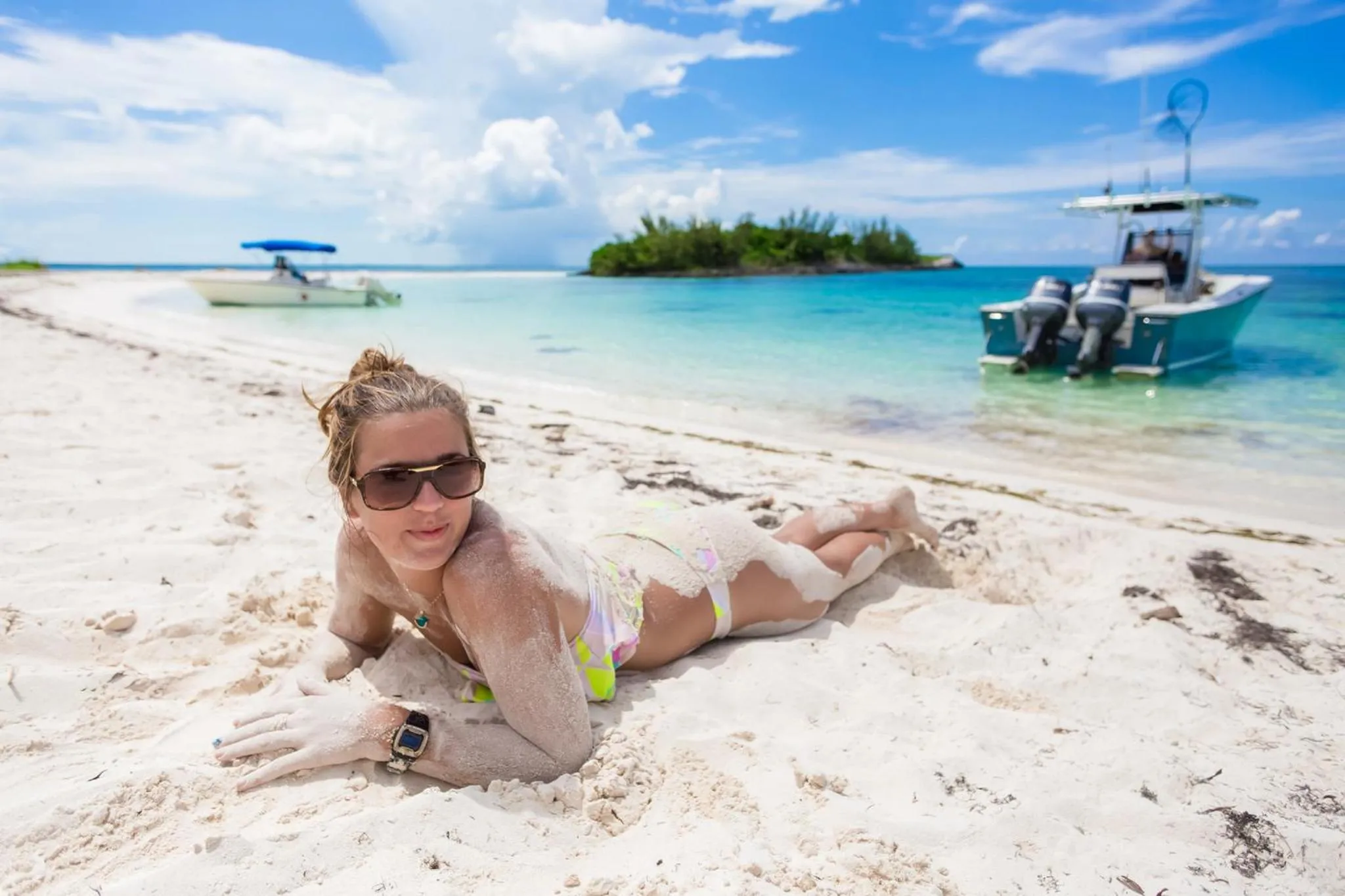 Une femme se repose sur une plage de sable blanc face à la mer.