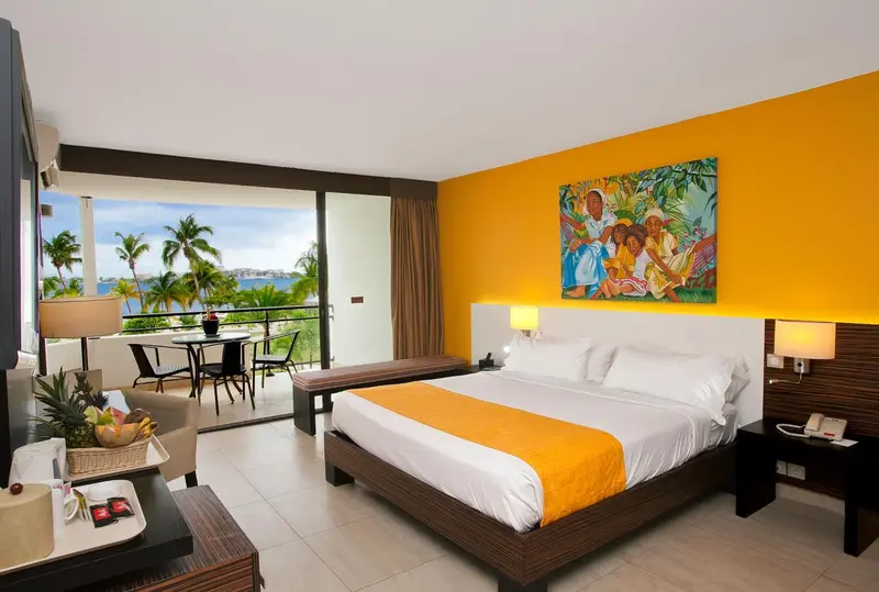 Chambre lumineuse avec un grand lit et une vue sur la mer.