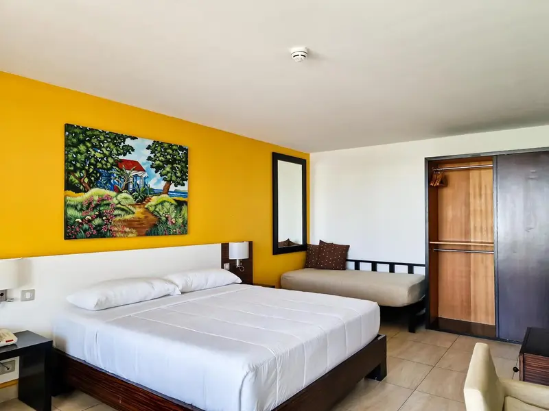 Une chambre lumineuse avec un grand lit et une décoration murale colorée.