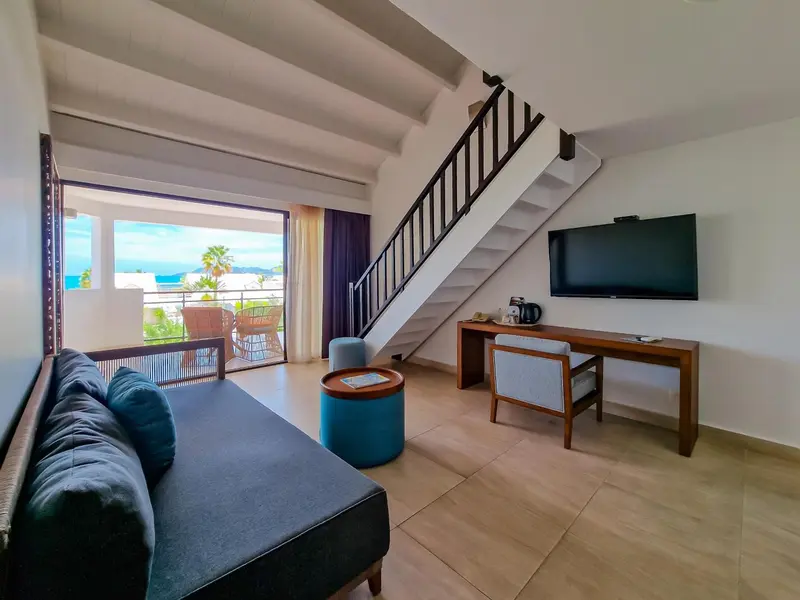 Un espace de vie intérieur lumineux avec canapé, bureau et accès à une terrasse.