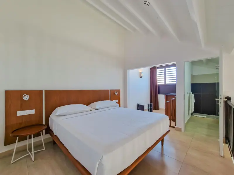 Une chambre lumineuse avec un grand lit recouvert de draps blancs.