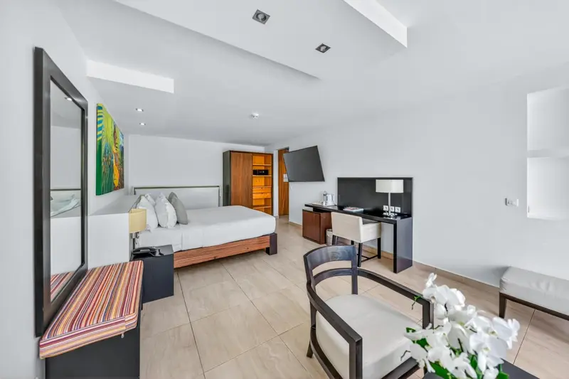 Une chambre lumineuse avec un grand lit et un espace bureau.