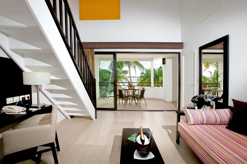 Espace de vie lumineux avec canapé, table basse et accès à une terrasse.