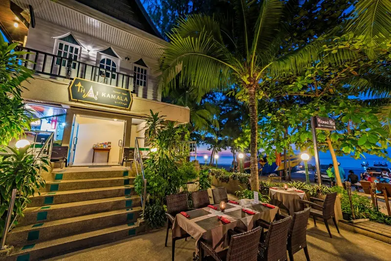 Terrasse d'un bâtiment avec tables et chaises, éclairée pour le dîner.