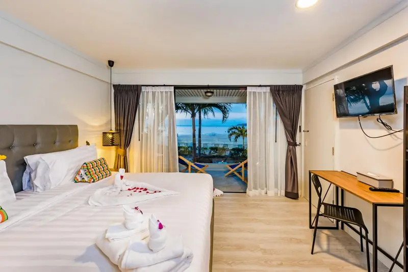 Une chambre lumineuse avec un grand lit donnant sur une terrasse et la mer.