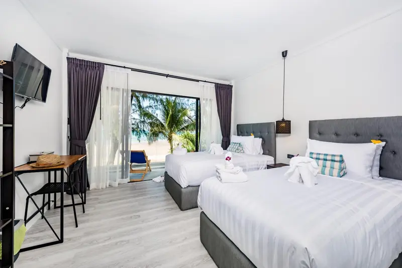 Une chambre lumineuse avec deux lits simples et vue sur la végétation.